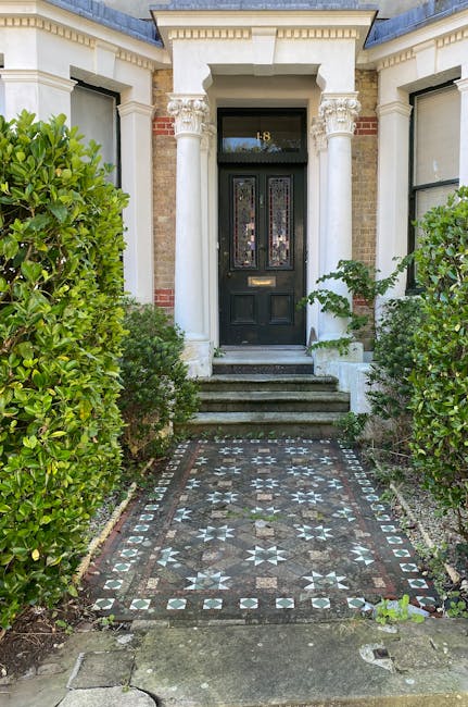 A detailed view of a garden showcasing neatly trimmed green hedges bordering a well-maintained lawn with vibrant grass, adjacent flower beds filled with colorful blooms, and a clean stone pathway runn